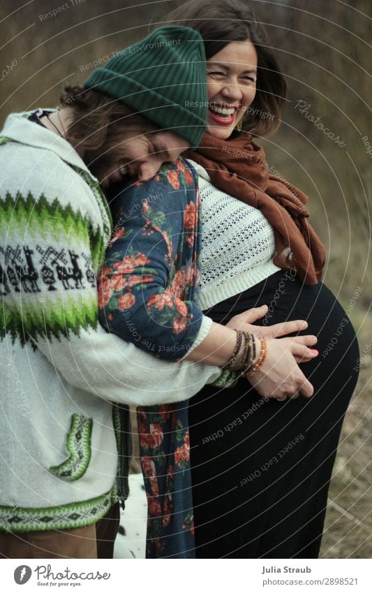 Heavily pregnant woman laughs and rejoices with her husband Parents Adults Couple Partner 2 Human being 30 - 45 years Scarf Cap Brunette Long-haired Beard Touch