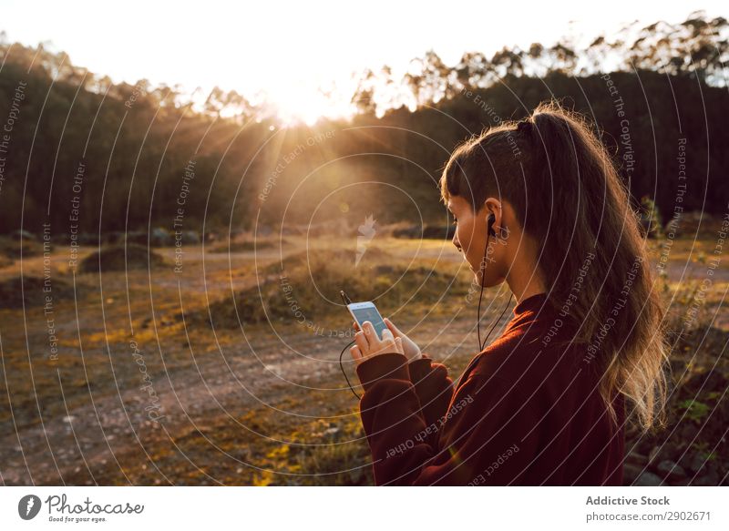 Young woman with piercing listening music on smartphone on hill Hipster Headphones PDA Music Listening Piercing Hill Landscape Street Youth (Young adults)