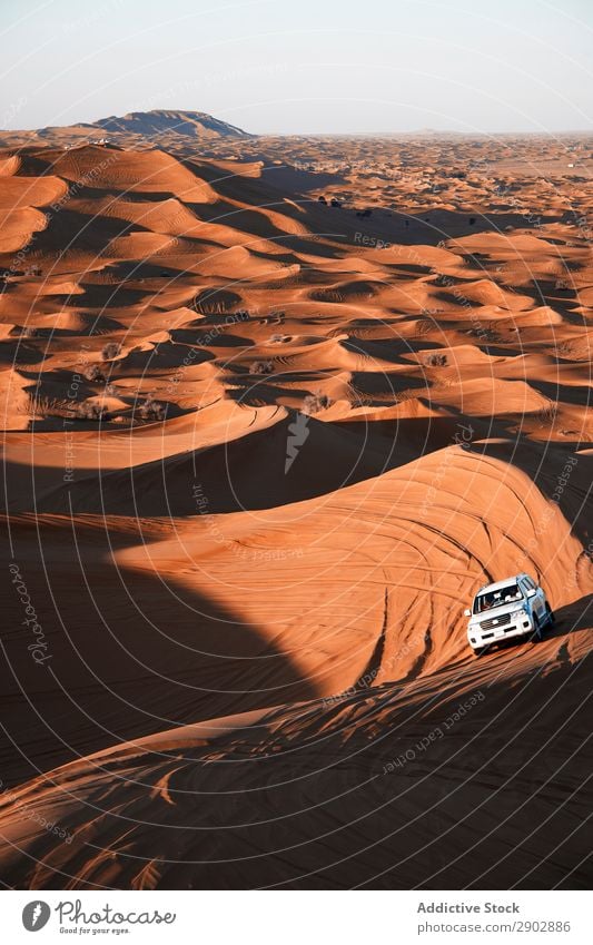 Automobile driving between hills in desert Car Desert Safari Dune off-roader Sand Dubai United Arab Emirates Driving Hill Beautiful weather Adventure