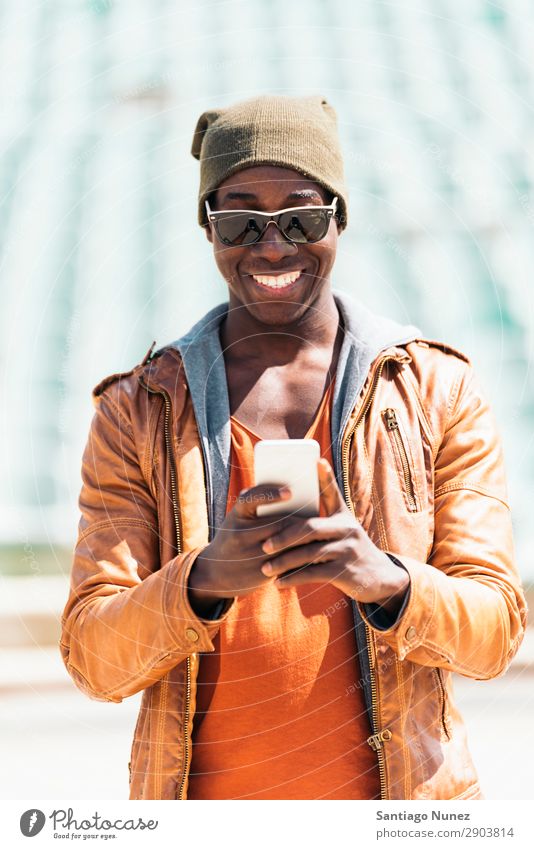 American man using mobile in the street. Man Telephone Cellphone Town African Black Mobile Youth (Young adults) Laughter PDA Technology Human being Happy