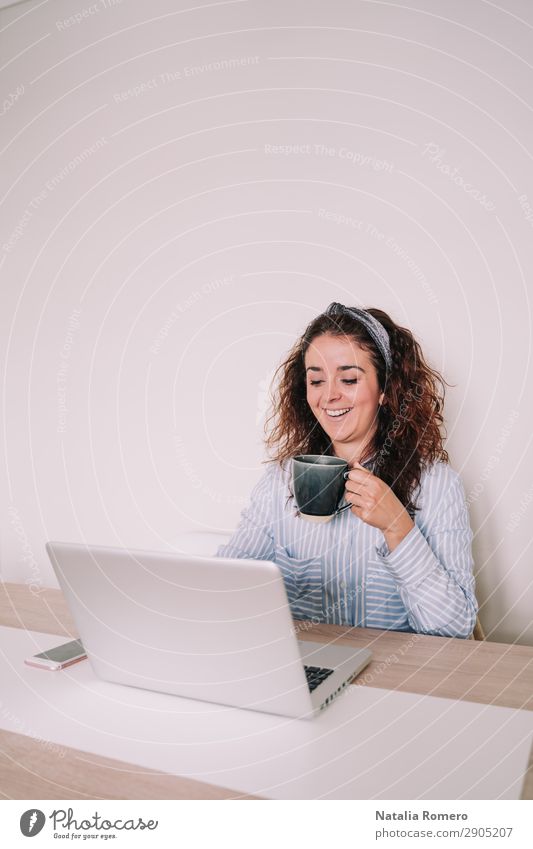 brunette woman is using her computer while having a coffee Coffee Lifestyle Happy Desk Table Work and employment Office Business Telephone Computer Notebook