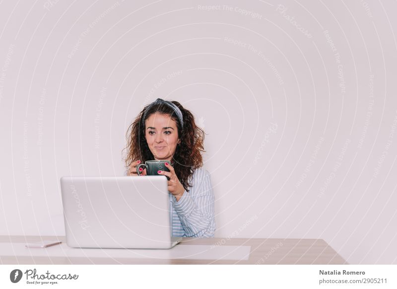 brunette woman is using her computer while having a coffee Coffee Lifestyle Happy Desk Table Work and employment Office Business Telephone Computer Notebook