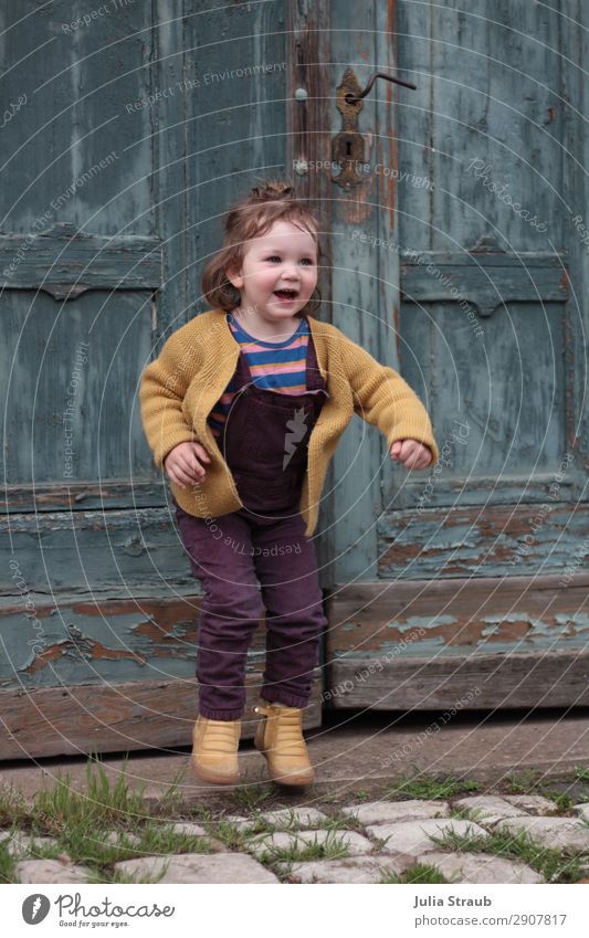 girl gate hopping fun Feminine Toddler Girl 1 Human being 1 - 3 years Königsberg Old town Gate Door Cobblestones Wooden door Cardigan Overalls Brunette