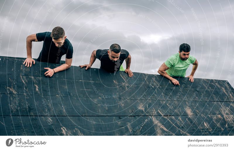 Participants in obstacle course climbing inverted wall Lifestyle Sports Climbing Mountaineering Human being Man Adults Group Authentic Strong Black Effort