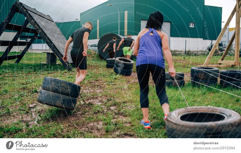 Group in obstacle course dragging wheels Sports Human being Woman Adults Man Grass Authentic Strong Black Power Effort obstacle course race pulling Tire athlete