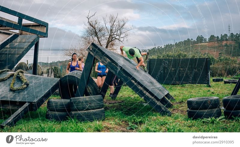 Participants in obstacle course climbing inverted wall Lifestyle Sports Climbing Mountaineering Human being Woman Adults Man Group Meadow Jump Authentic Strong