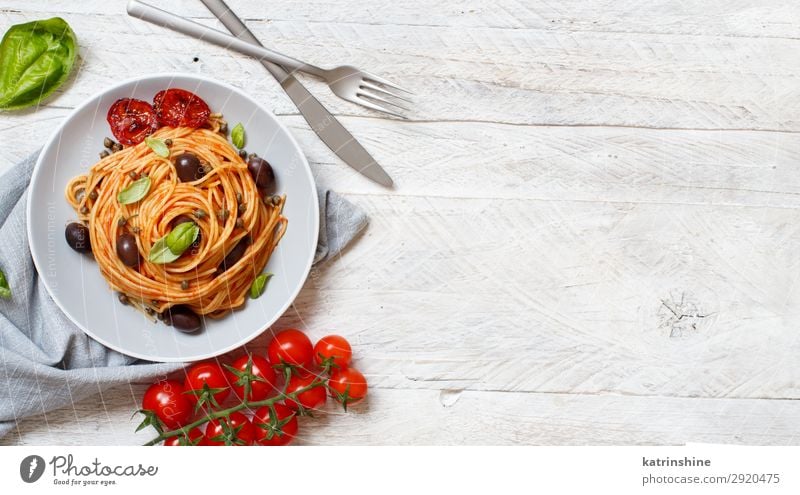 Spaghetti with tomato sauce olives and capers Vegetable Lunch Dinner Vegetarian diet Plate Fork Wood Above Green Red Tradition pasta puttanesca Olive Basil