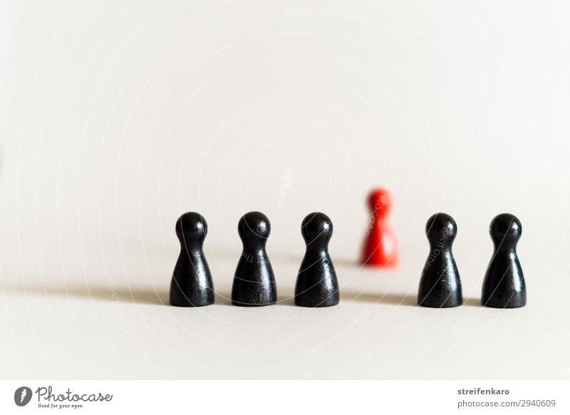 A single red toy figure stands apart behind a row of black toy figures Playing Board game Group Toys Wood Exceptional Rebellious Red Black Agreed Together