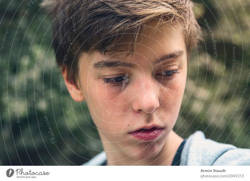 Portrait of a young man looking down, lost in thought pensive portrait teenager serious thoughtful concentration boy male beautiful casual caucasian outdoor