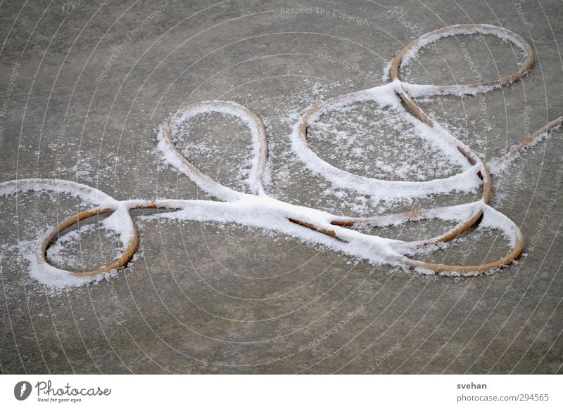 Something winding Cable Rope Concrete Line Bow Lie Gray White Snow Loop Winter power cable Muddled Untidy Wiggly line Colour photo Exterior shot Detail Abstract