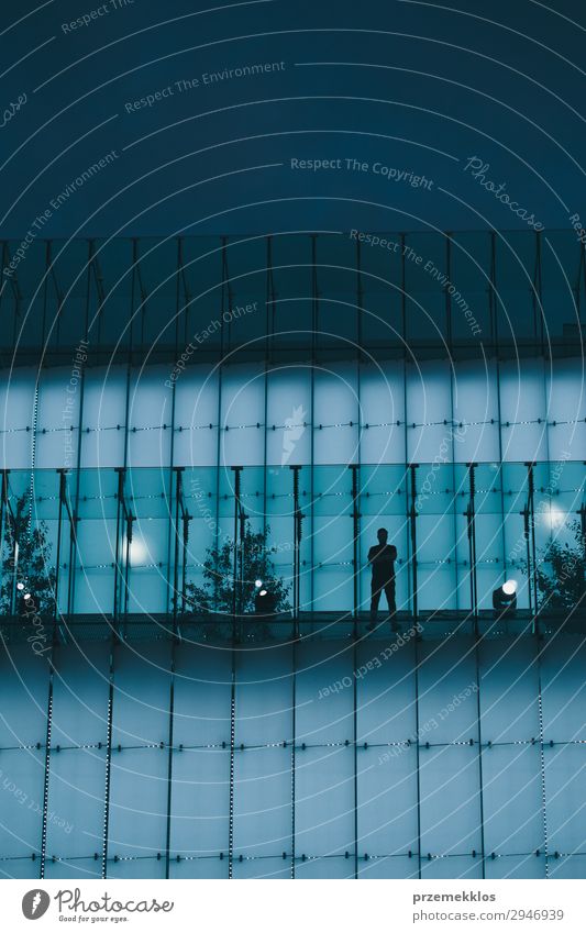 Man standing on backlit glass construction in a city center Adults Town Downtown Building Blue City light wall Evening Night Silhouette