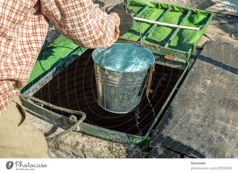 Farmer with gloves drawing water from an old well. Lifestyle Athletic Wellness Harmonious Leisure and hobbies Vacation & Travel Freedom Summer Summer vacation