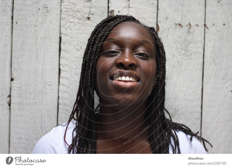 be happy! Young woman Youth (Young adults) Head Hair and hairstyles Mouth T-shirt Black-haired Long-haired Dreadlocks Afro Wooden wall Observe To enjoy Smiling