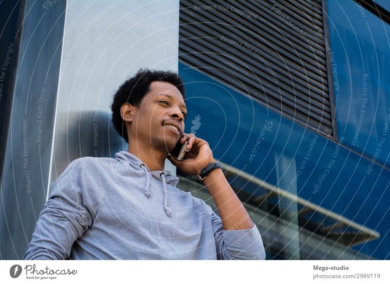 Young latin man talking on mobile phone outside. Lifestyle Style Happy Face Business To talk Telephone PDA Technology Human being Man Adults Street Smiling Sit