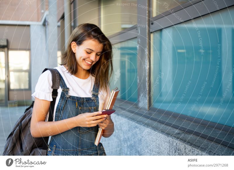 Happy student girl using smart phone at the school corridor Lifestyle Beautiful School Academic studies Telephone PDA Technology Woman Adults