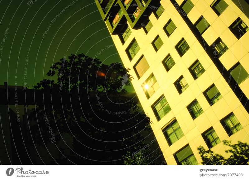 An appartment building, colored in gold by the setting sun, and a dark blue sky behind it Sun Living or residing House (Residential Structure) Building Town