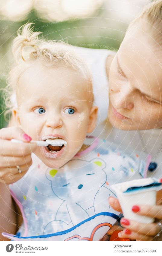 A baby girl is spoon fed with yogurt by her mother Yoghurt Dessert Eating Spoon Child Human being Feminine Baby Girl Young woman Youth (Young adults) Mother