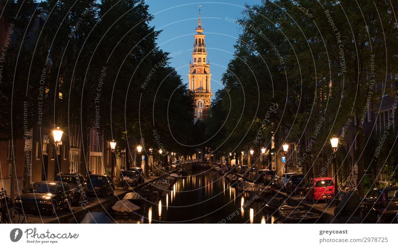 Amsterdam cityscape at night. Scene with boats on the canal lined with lanterns and Zuiderkerk, 17th-century Protestant church Vacation & Travel Tourism