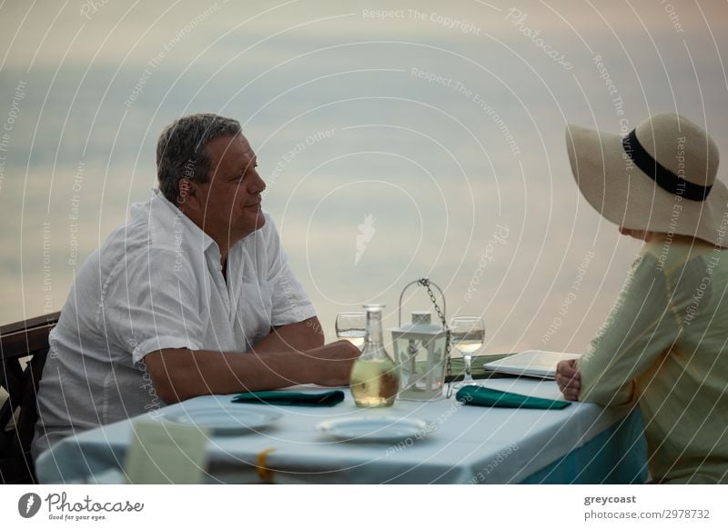 Mature couple having romantic evening. They enjoying the time and looking at each other sitting at the table in waterfront restaurant Dinner Happy Relaxation