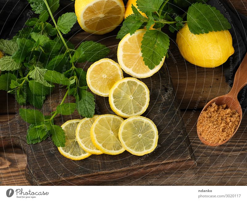 sliced yellow lemons on a brown wooden board Fruit Vegetarian diet Diet Lemonade Juice Spoon Summer Table Nature Leaf Wood Eating Fresh Natural Juicy Brown