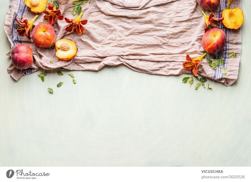 Food background with fresh whole and half peaches on kitchen towel with leaves, flowers and copy space for your design or product , top view. Flat lay. Horizontal. Border