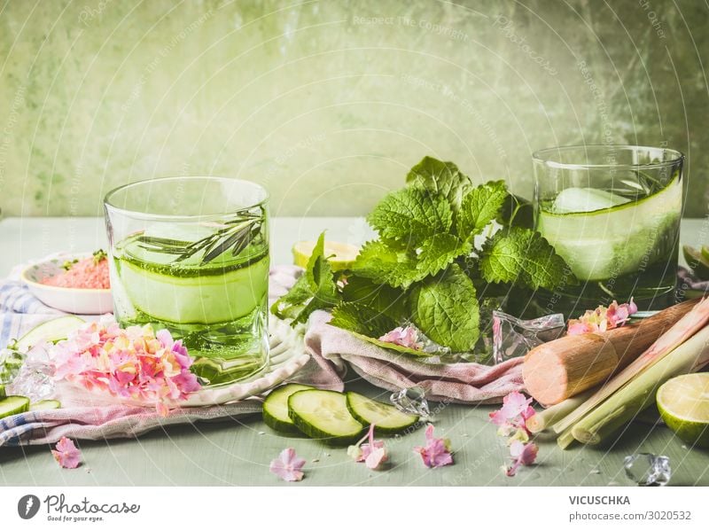 Classes with cucumber lemonade or detox infused water and ice cubes on table with ingredients. Green color summer refreshing drinks preparation classes green