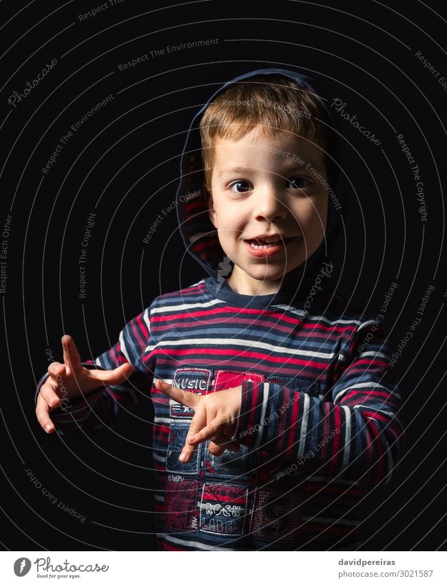 Happy boy with hoodie looking at camera over black background Joy Face Child Schoolchild Human being Boy (child) Man Adults Infancy Hand Fingers Clothing Shirt