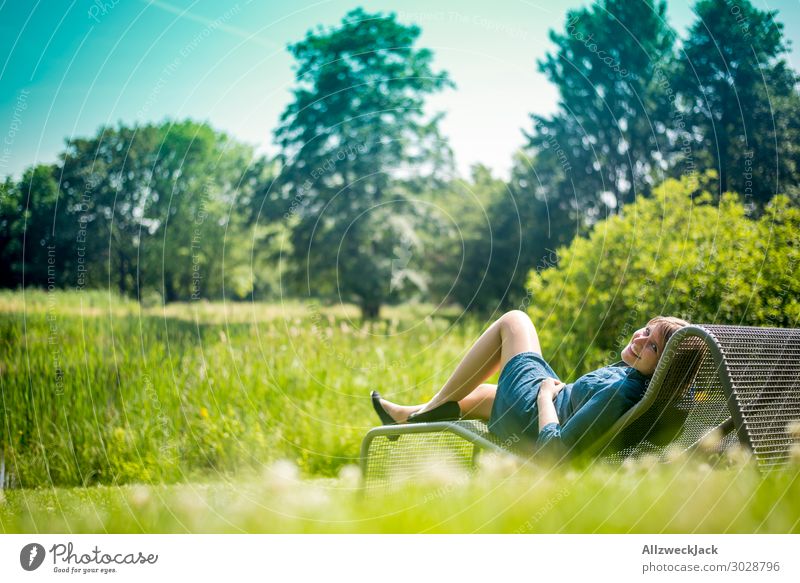 young woman sunbathing on a couch in the garden Beautiful weather Cloudless sky Blue sky Green Nature Meadow Lawn Couch Sunbathing To enjoy Relaxation Break