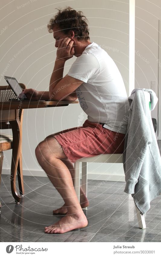 Man sits on chair and works on laptop Notebook Tablet computer T-shirt Pants Jacket brunette Short-haired Curl Work and employment Observe Think Study Reading