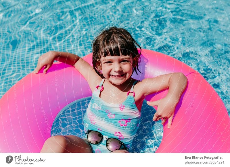 beautiful kid girl floating on pink donuts in a pool Lifestyle Joy Happy Beautiful Relaxation Swimming pool Leisure and hobbies Vacation & Travel Summer Sun