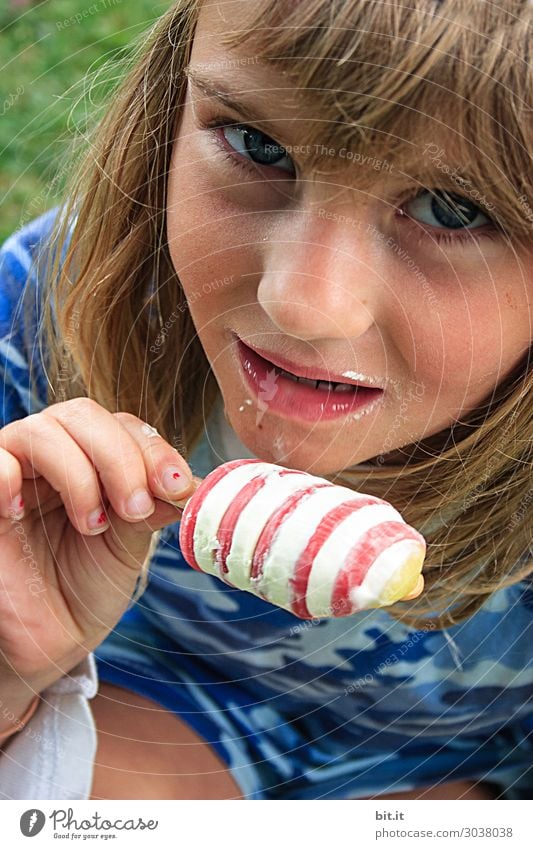 Blonde girl with pony and smeared mouth eats ice cream, with curls of milk, on a meadow and looks friendly into the camera Vacation & Travel Tourism Human being