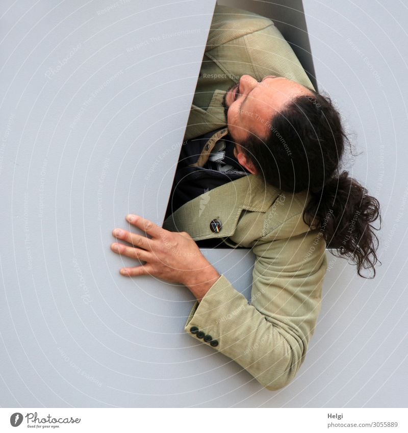 Portrait of a man with long dark hair, beard and beige jacket, looking up through an opening Human being Masculine Man Adults Head Hair and hairstyles Arm Hand