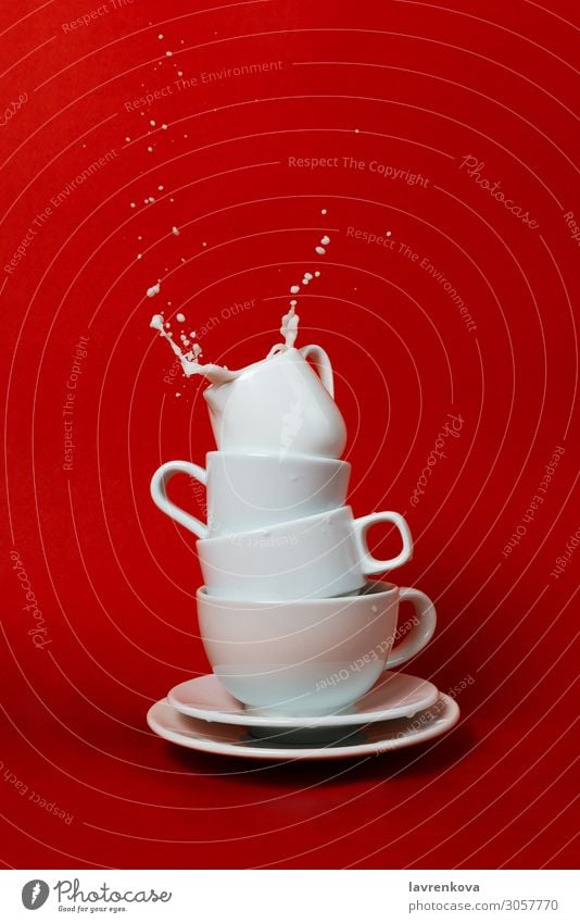 cups and saucers with creamer on top and splash inside Beverage Breakfast Coffee Cup dishware Drop Fluid Liquid Milk Morning Movement Mug Red Saucer soy Splash