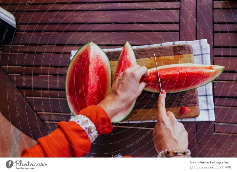 young woman preparing a healthy recipe of diverse fruits, watermelon, orange and blackberries. Using a mixer. Homemade, indoors, healthy lifestyle