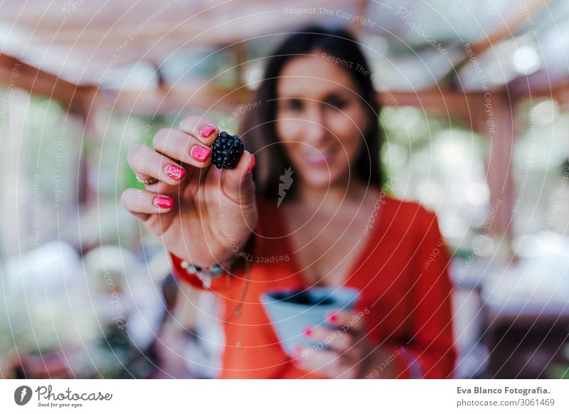 young woman holding a bowl of blackberries. preparing a healthy recipe of diverse fruits, watermelon, orange and blackberries. Using a mixer. Homemade, indoors, healthy lifestyle. selective focus