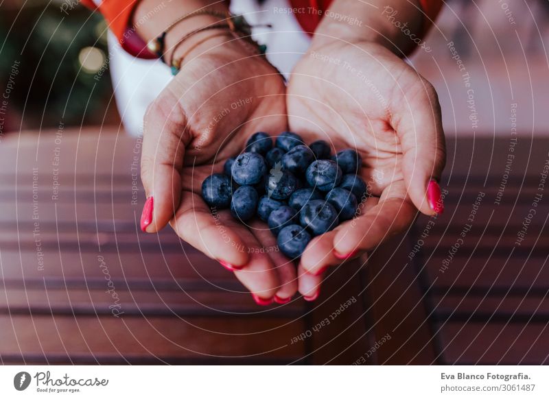 young woman holding a bowl of blueberries. preparing a healthy recipe of diverse fruits, watermelon, orange and blackberries. Using a mixer. Homemade, indoors, healthy lifestyle