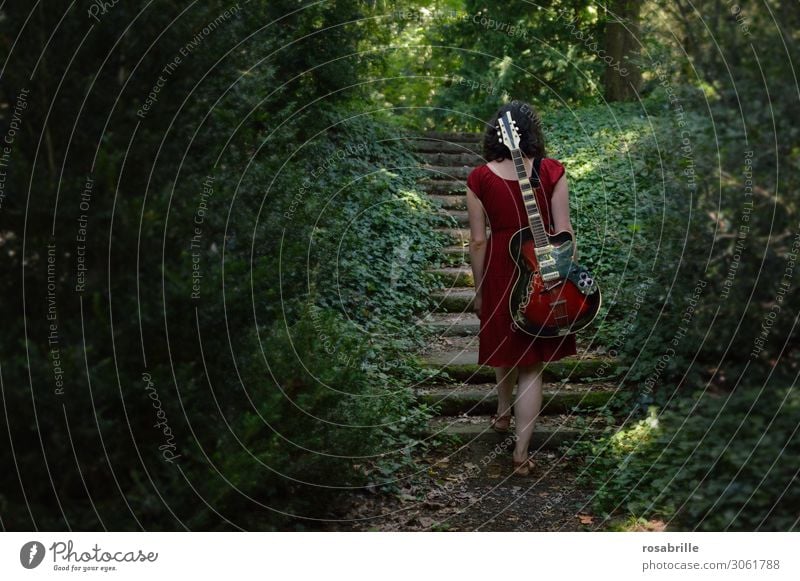 on the road again - musical ascent - brunette young woman walks through the forest with red guitar on her back | alone with guitar in the forest