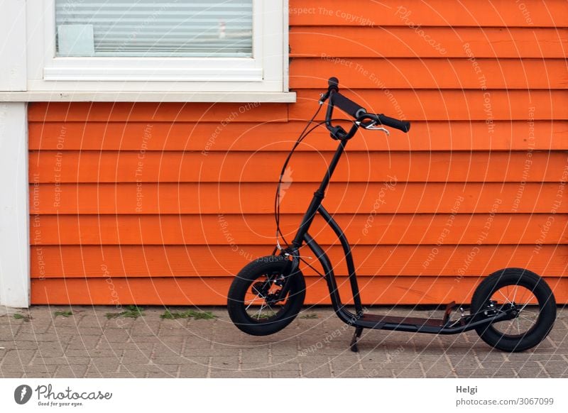 black scooter stands in front of a wooden orange wooden wall with window House (Residential Structure) Wall (barrier) Wall (building) Facade Window Footpath