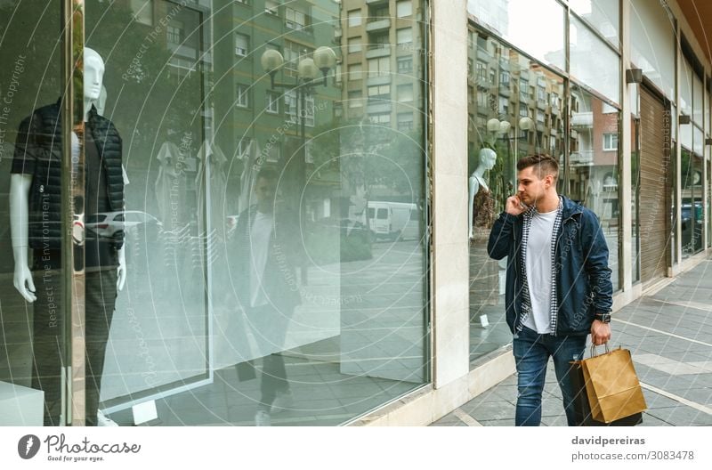 Man with shopping bags in front clothing store Lifestyle Shopping Style To talk PDA Human being Adults Fashion Clothing Jeans Authentic young walking Storefront