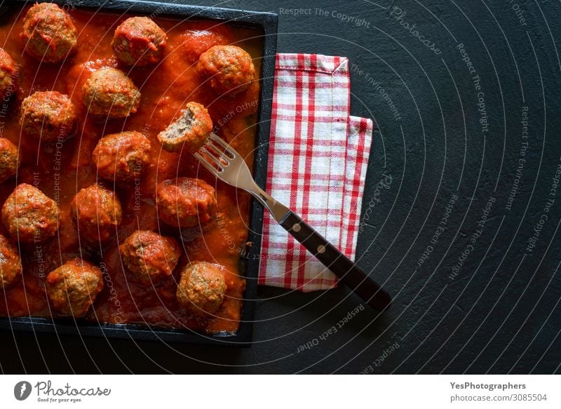 Meatballs in tomato sauce on black tray. Above view of meat dish Eating Lunch Dinner Plate Fork Table Restaurant Dark Delicious Red above view bitten