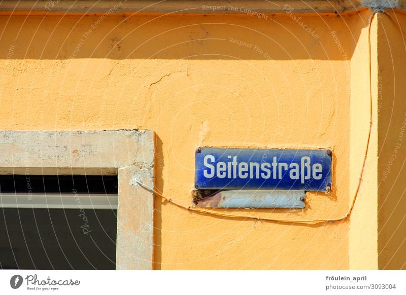 side street House (Residential Structure) Wall (barrier) Wall (building) Signs and labeling Funny Blue Yellow Strange Street sign Colour photo Exterior shot Day