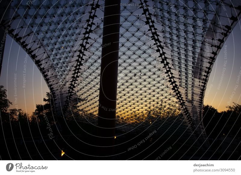 Twilight sets in on the campus in Bad Neustadt an der Saale. A big net with a pillar and bushes in the background. Elegant Design Environment Nature Sunrise