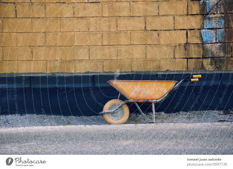 old yellow wheelbarrow on the street Wheelbarrow Metal Old Construction worker Equipment Tool Work and employment Transport Yellow Street Exterior shot Build