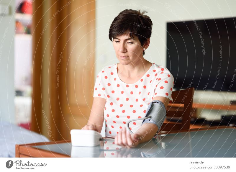 Woman measuring her own blood pressure at home. Health care Illness Medication Examinations and Tests Screen Tool Human being Feminine Adults Arm 1