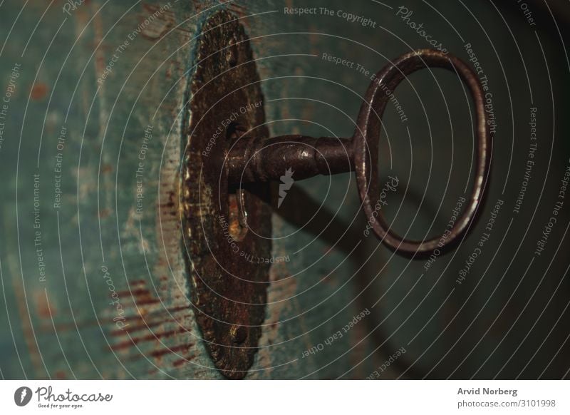 An old rusty key in a lock of a blue wooden door access aged antique background brown close closeup concept design drawer forbidden hole home inside keyhole