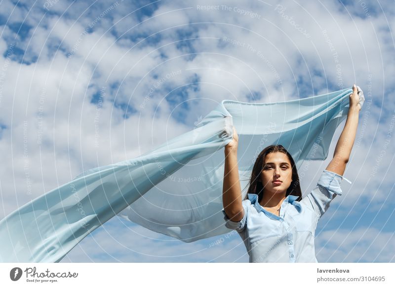 Young female holding cut of blue cloth up in the sky Adults Air Loneliness Attractive Blue Cloth Clouds Cut Woman Freedom Young woman Hand Happy Height Horizon