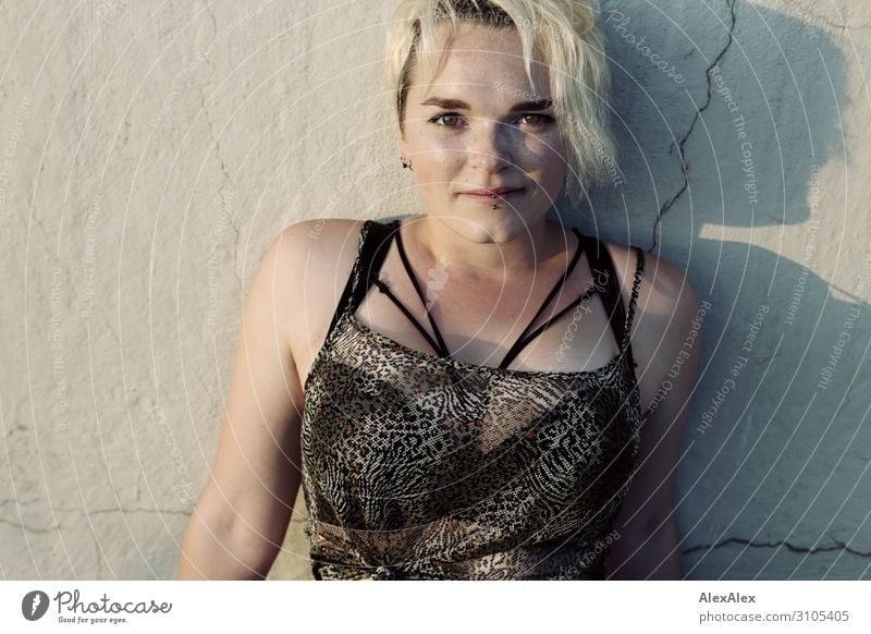 Portrait of a young woman with freckles and dimples leaning against a concrete wall and looking into the camera Style Joy pretty Life Summer Young woman