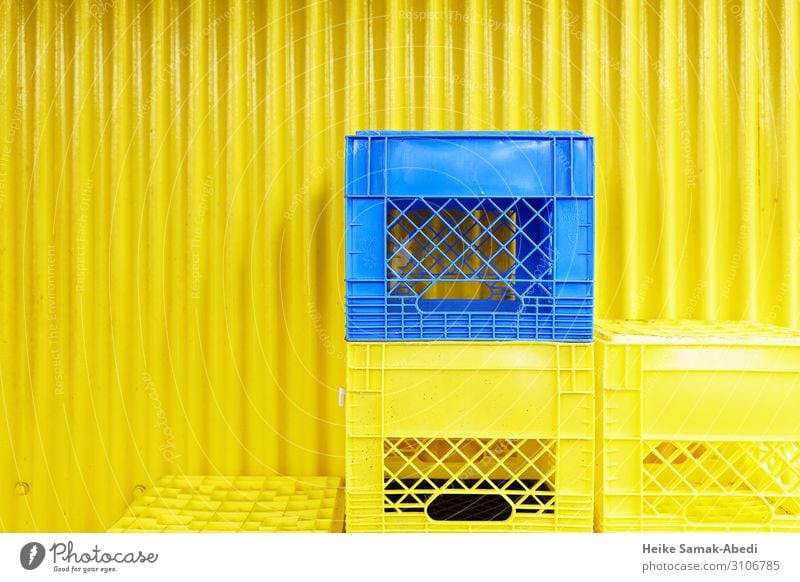 Yellow and blue boxes in front of a yellow corrugated iron wall Shopping Wall (barrier) Wall (building) Facade Box Plastic Blue Containers and vessels Stack