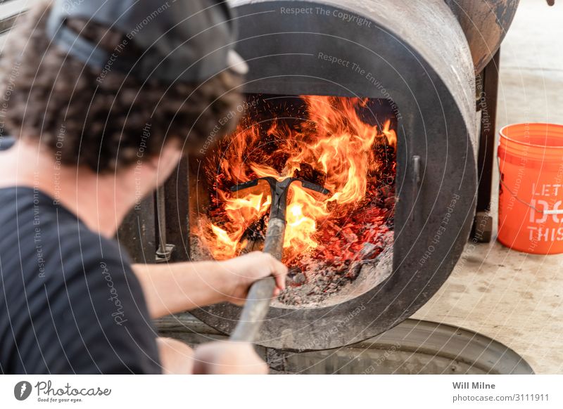 Man Stoking Fire in a Smoker Barbecue (apparatus) Barbecue (event) BBQ Barbecue area Meat Wood Flame Hot Heat Shovel Cooking smoking Food