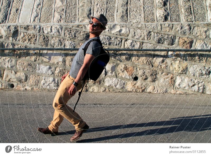 A man with sunglasses, hat and rucksack walks down a street in a corridor leaning far back Masculine Young man Youth (Young adults) Man Adults 1 Human being